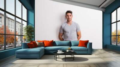 A cheerful young hispanic man standing in a studio. Wall mural