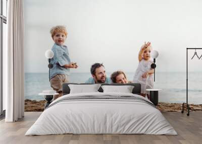 A family with two toddler children lying on sand beach on summer holiday. Wall mural