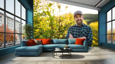 A front view of mature farmer standing in orchard at sunset. Copy space. Wall mural