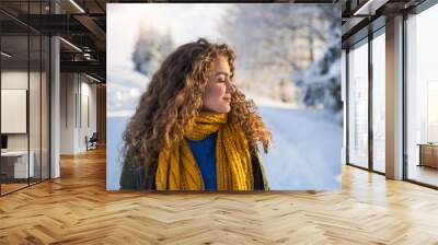 A front view portrait of young woman standing outdoors in snowy winter forest. Wall mural