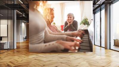 A girl with mother and grandmother playing the piano. Wall mural