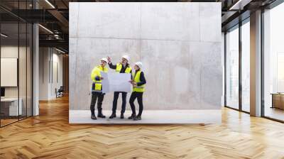 A group of engineers standing against concrete wall on construction site. Wall mural