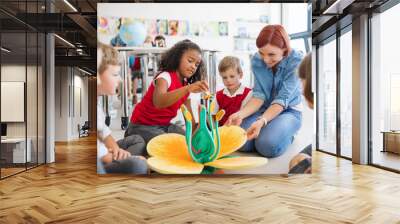 A group of small school kids with teacher sitting on the floor in class, learning. Wall mural