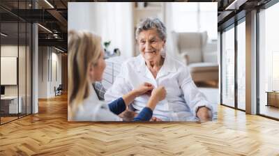 A health visitor helping a sick senior woman sitting on bed at home. Wall mural