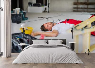 A man worker lying on the floor after an accident at the construction site. Wall mural