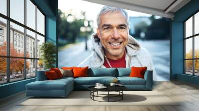 A portrait of an active mature man standing outdoors in city, wearing hoodie. Wall mural