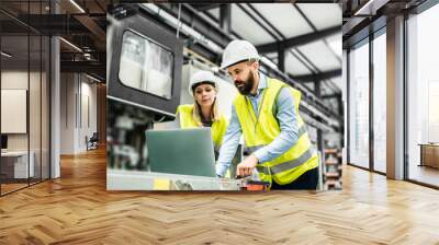 a portrait of an industrial man and woman engineer with laptop in a factory, working. Wall mural