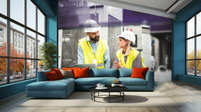 A portrait of an industrial man and woman engineer with laptop in a factory, working. Wall mural