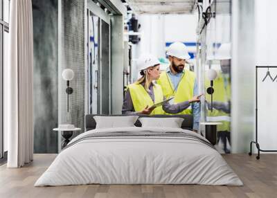 a portrait of an industrial man and woman engineer with tablet in a factory, working. Wall mural