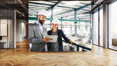 A portrait of an industrial man and woman engineer with tablet in a factory, working. Wall mural