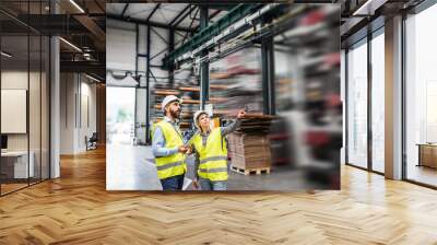 a portrait of an industrial man and woman engineer with tablet in a factory, working. Wall mural