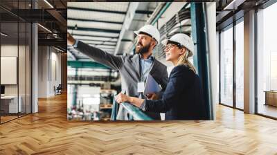 A portrait of an industrial man and woman engineer with tablet in a factory, working. Wall mural