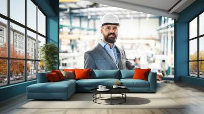 A portrait of an industrial man engineer standing in a factory. Wall mural