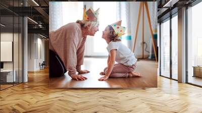 A portrait of small girl with grandmother having fun at home. Wall mural