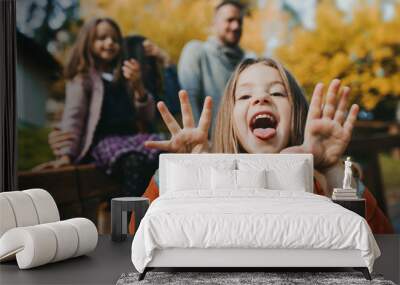 A portrait of small girl with her family in town in autumn. Wall mural