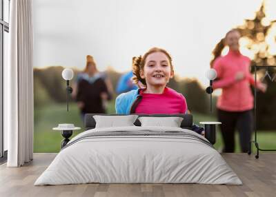 A portrait of small girl with large group of people running in nature. Wall mural