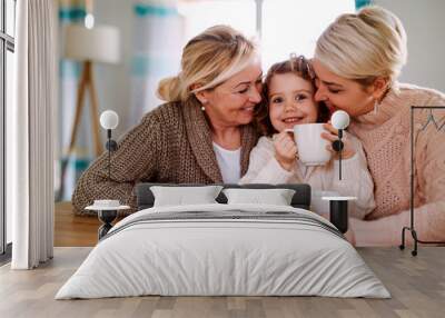 A portrait of small girl with mother and grandmother at the table at home. Wall mural