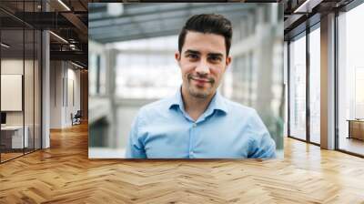 A portrait of young businessman standing indoors in an office. Wall mural