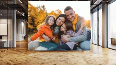 A portrait of young family with two small children in autumn nature at sunset. Wall mural