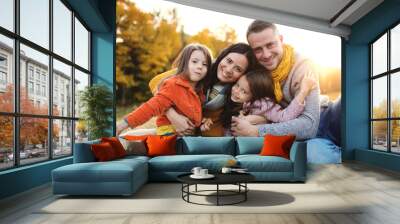 A portrait of young family with two small children in autumn nature at sunset. Wall mural