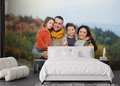 A portrait of young family with two small children in autumn nature. Wall mural