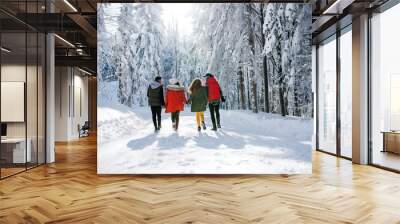 A rear view of group of young friends on a walk outdoors in snow in winter forest. Wall mural