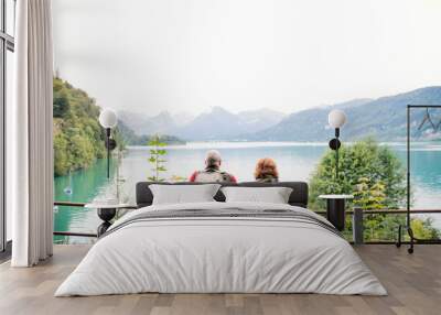 A rear view of senior pensioner couple standing by lake in nature. Wall mural