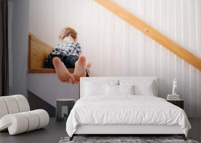 A rear view of small girl lying down on staircase. Copy space. Wall mural