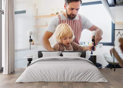 A small boy with father indoors in kitchen making pancakes. Wall mural