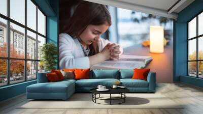 A small girl praying at home. Wall mural