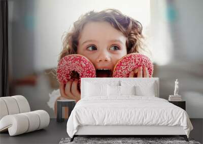 A small girl with doughnuts at home, looking at camera. Wall mural