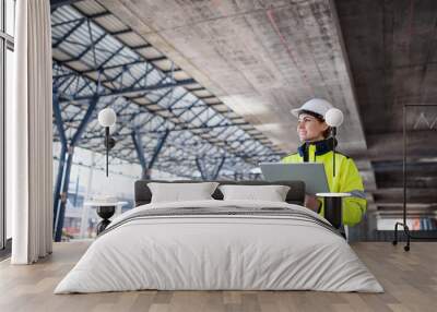 A woman engineer with tablet standing on construction site, working. Wall mural