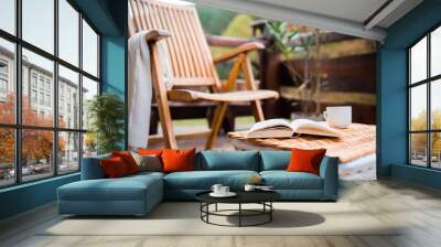 A wooden chair and a book on a basket on a terrace on a sunny day in autumn. Wall mural