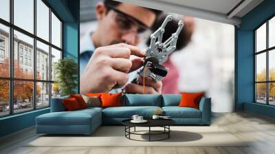 A young businessman or scientist with robotic hand standing in office, working. Wall mural