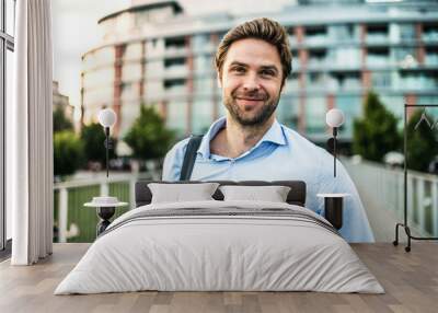 A young businessman with a bag walking on a bridge. Wall mural