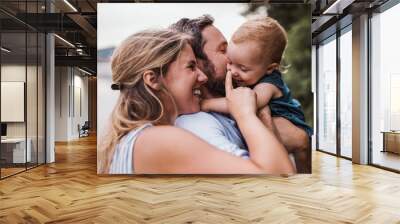 A young family with a toddler girl outdoors by the river in summer. Wall mural