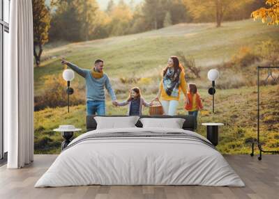 A young family with two small children walking in autumn nature. Wall mural