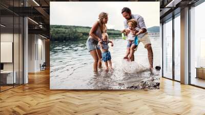 A young family with two toddler children outdoors by the river in summer. Wall mural