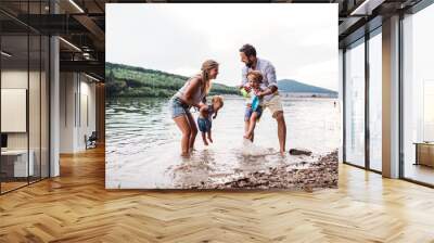 A young family with two toddler children outdoors by the river in summer. Wall mural