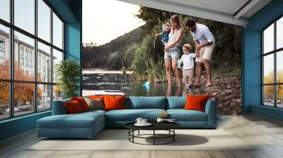 A young family with two toddler children outdoors by the river in summer. Wall mural