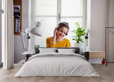 A young female student sitting at the table, using laptop when studying. Wall mural