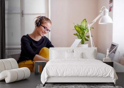 A young female student sitting at the table, using tablet when studying. Wall mural