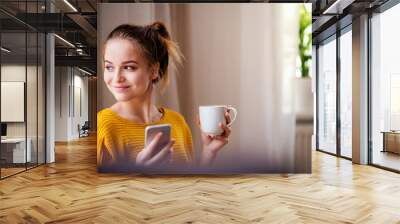 A young female student with coffee and smartphone resting. Wall mural