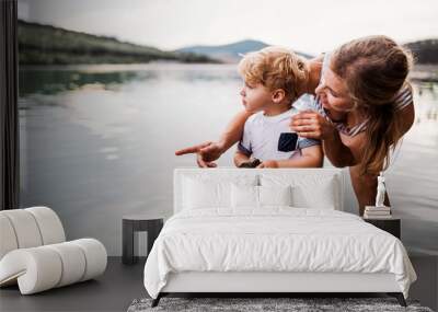 A young mother with a toddler boy outdoors by the river in summer. Wall mural