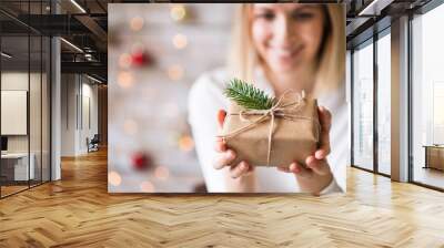 A young woman holding wrapped Christmas present. Wall mural