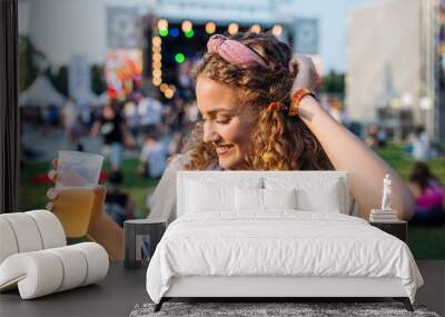 A young woman with drink dancing at summer festival. Wall mural