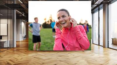 A young woman with group of people doing exercise in nature, resting. Wall mural