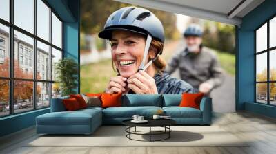 Active senior couple with electrobikes standing outdoors on a road in nature. Wall mural