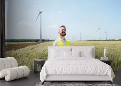 An engineer standing on a field on wind farm, making notes. Wall mural