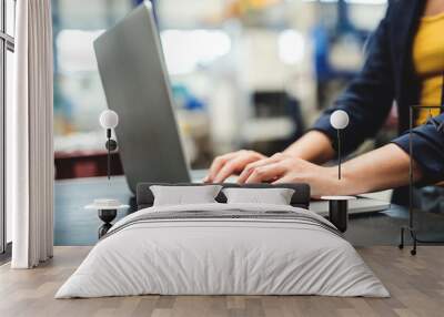 An industrial woman engineer in a factory with laptop, typing. Wall mural